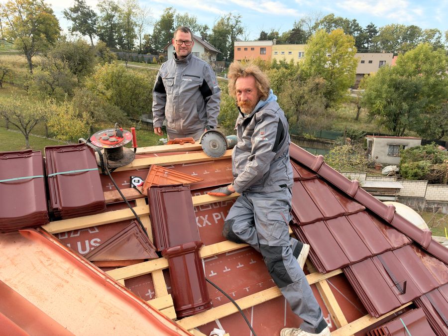 Dva pokrývači PROIZOL na rozdělané střeše s taškami a úhlovou bruskou.